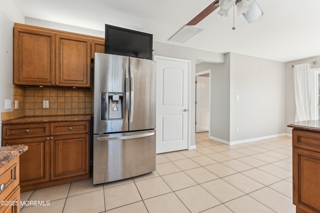 kitchen featuring decorative backsplash, dark stone countertops, brown cabinets, and stainless steel fridge with ice dispenser