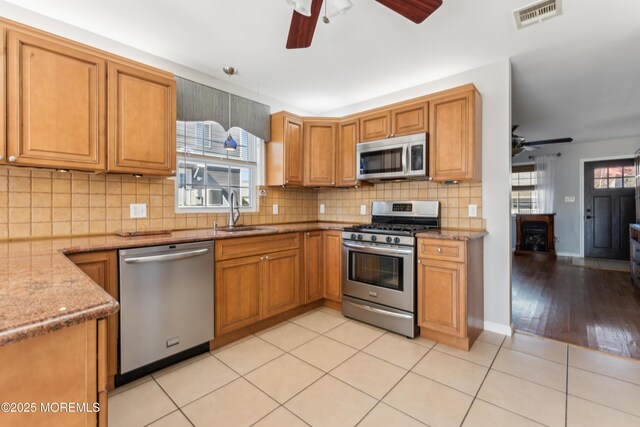 kitchen with light tile patterned floors, visible vents, appliances with stainless steel finishes, light stone countertops, and a sink