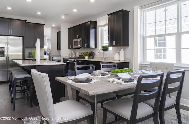 kitchen featuring light stone countertops, sink, dark wood-type flooring, a kitchen island, and appliances with stainless steel finishes