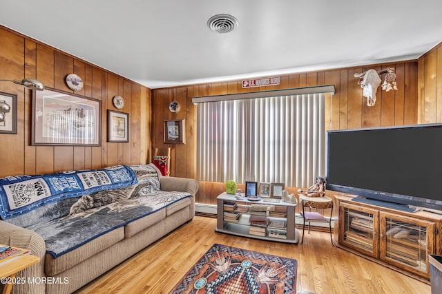 living room featuring wood walls, light wood-type flooring, and baseboard heating