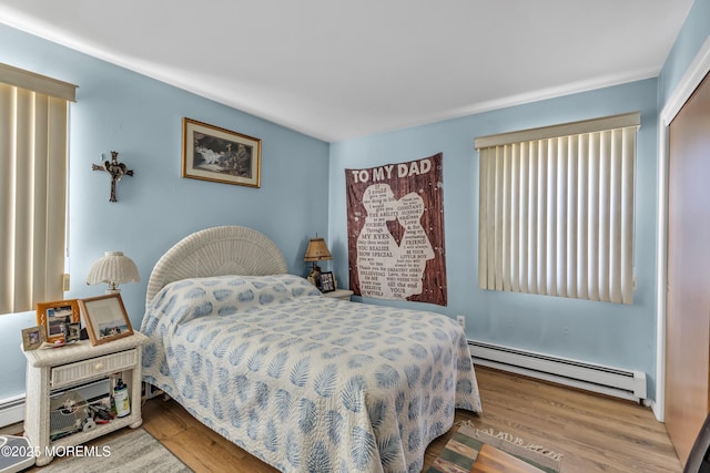 bedroom with hardwood / wood-style floors and a baseboard radiator