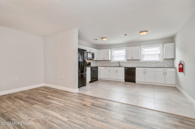 kitchen featuring white cabinetry, sink, black appliances, and light wood-type flooring