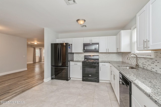 kitchen featuring white cabinets, sink, light stone countertops, and black appliances