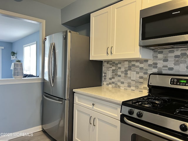 kitchen featuring white cabinets, stainless steel appliances, and decorative backsplash