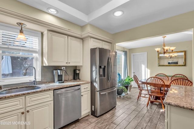 kitchen featuring appliances with stainless steel finishes, backsplash, sink, a chandelier, and hanging light fixtures