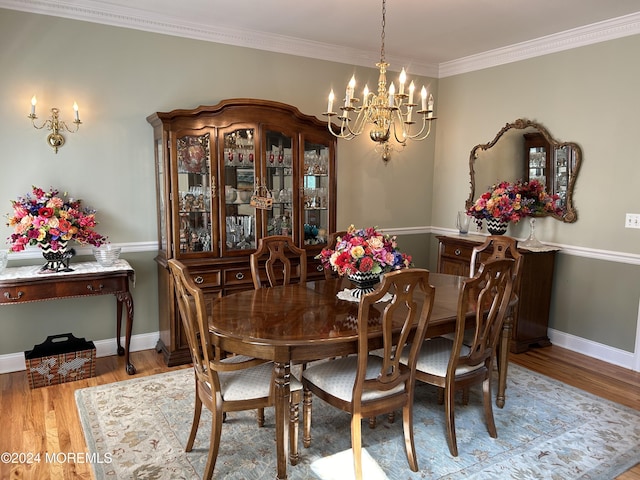 dining area with light wood-type flooring, an inviting chandelier, and ornamental molding