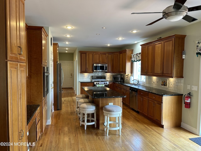 kitchen featuring sink, a center island, light hardwood / wood-style flooring, a kitchen bar, and appliances with stainless steel finishes