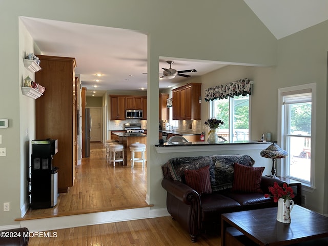 living room featuring light wood-type flooring, vaulted ceiling, ceiling fan, and sink