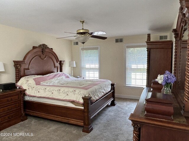 carpeted bedroom with ceiling fan and multiple windows