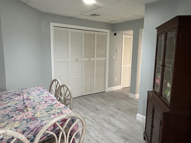 bedroom with a closet, a drop ceiling, and light wood-type flooring