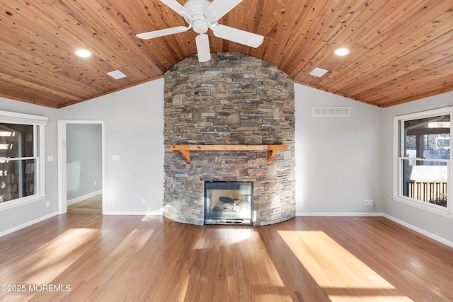 unfurnished living room featuring hardwood / wood-style floors, vaulted ceiling, a stone fireplace, and wood ceiling