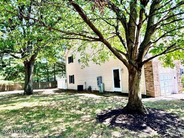 view of side of property with a lawn, central air condition unit, and a garage