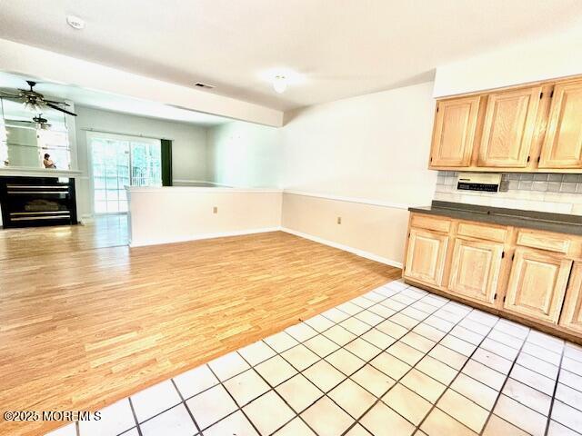 kitchen with backsplash, light brown cabinetry, and light hardwood / wood-style flooring