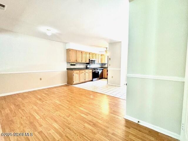 kitchen featuring light wood-type flooring, range, and tasteful backsplash