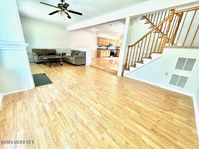 living room featuring ceiling fan, light hardwood / wood-style floors, and beam ceiling