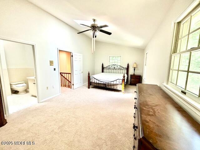 bedroom with connected bathroom, ceiling fan, carpet, and vaulted ceiling