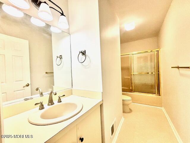 full bathroom featuring tile patterned flooring, vanity, toilet, and bath / shower combo with glass door