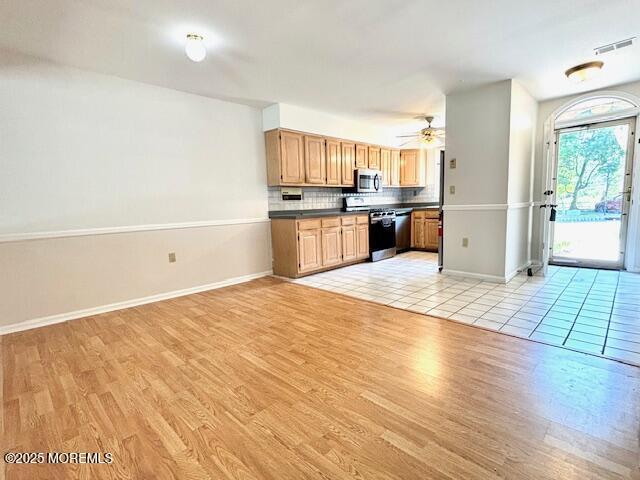 kitchen featuring ceiling fan, light wood-type flooring, backsplash, and range