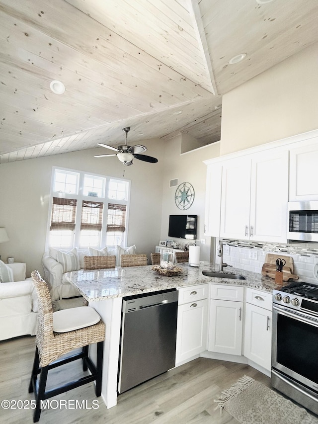 kitchen with sink, wooden ceiling, white cabinetry, light stone countertops, and appliances with stainless steel finishes