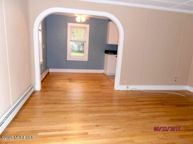 unfurnished dining area with a baseboard radiator and light hardwood / wood-style floors