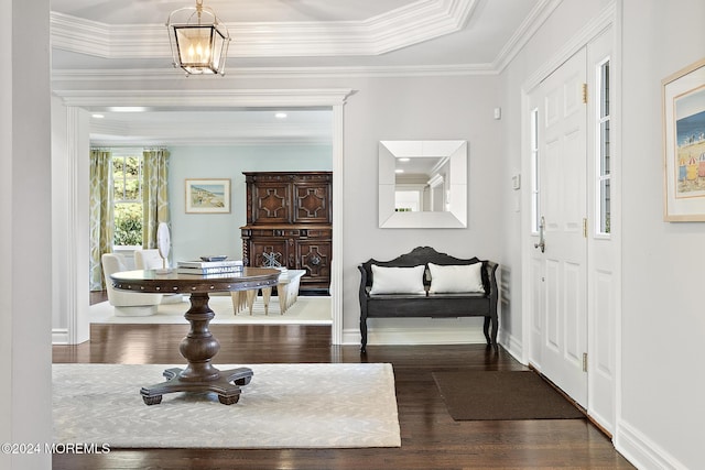 entryway with dark hardwood / wood-style flooring, a raised ceiling, crown molding, and an inviting chandelier