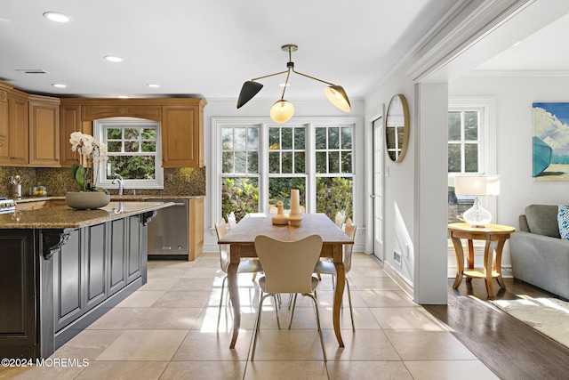 dining area with plenty of natural light, crown molding, and light tile patterned flooring