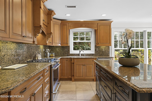 kitchen featuring decorative backsplash, light stone countertops, sink, light tile patterned floors, and stainless steel stove