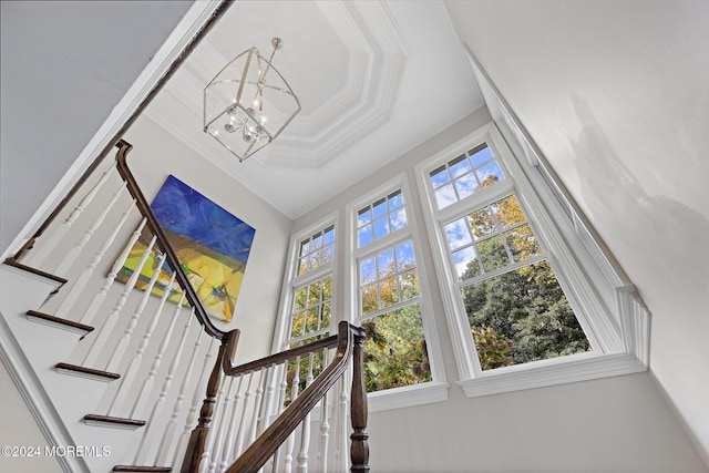 staircase featuring ornamental molding and a notable chandelier