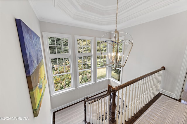 staircase with ornamental molding, a tray ceiling, hardwood / wood-style flooring, and a notable chandelier