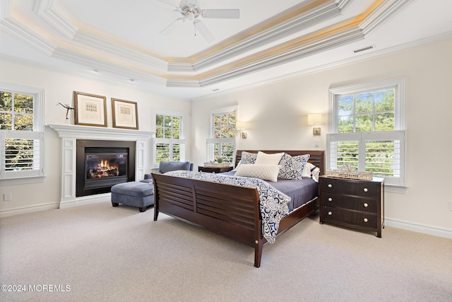 carpeted bedroom with a tray ceiling, ceiling fan, and ornamental molding