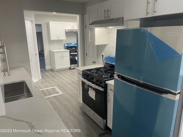 kitchen featuring white cabinets, backsplash, stainless steel appliances, and light hardwood / wood-style floors