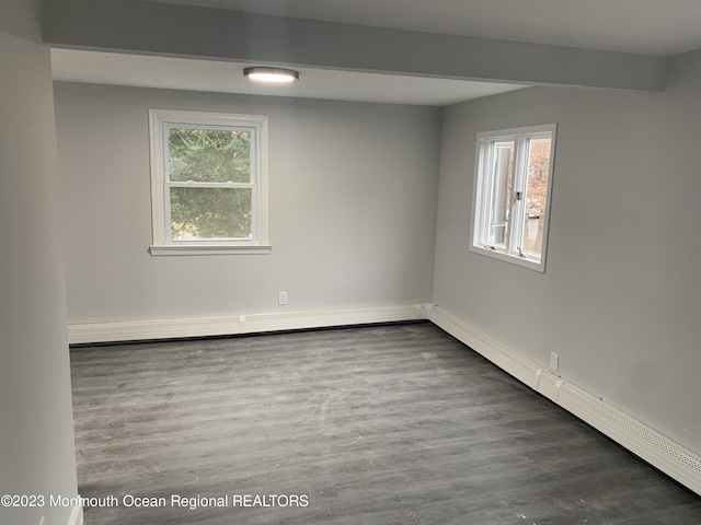 empty room with dark hardwood / wood-style floors and a baseboard heating unit