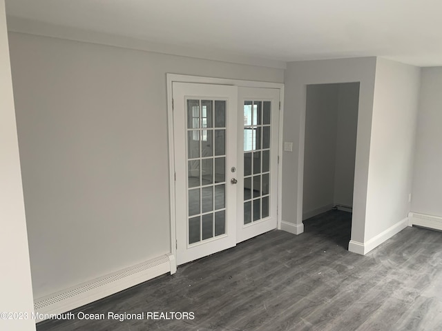 spare room featuring dark hardwood / wood-style floors, baseboard heating, and french doors