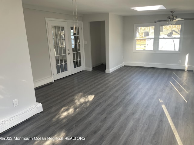 empty room with french doors, a skylight, ceiling fan, dark hardwood / wood-style floors, and baseboard heating