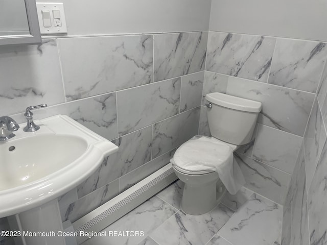 bathroom featuring toilet, sink, and a baseboard heating unit