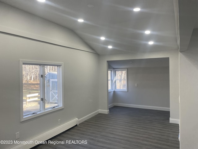 unfurnished room with baseboard heating, plenty of natural light, dark hardwood / wood-style floors, and lofted ceiling