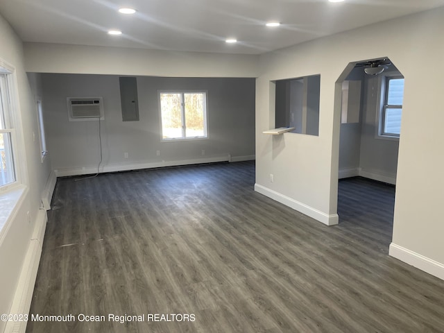 unfurnished room with a wall mounted air conditioner, electric panel, a baseboard heating unit, ceiling fan, and dark hardwood / wood-style flooring