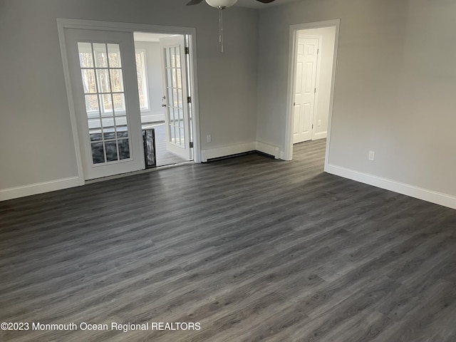 empty room featuring baseboard heating, ceiling fan, and dark hardwood / wood-style floors