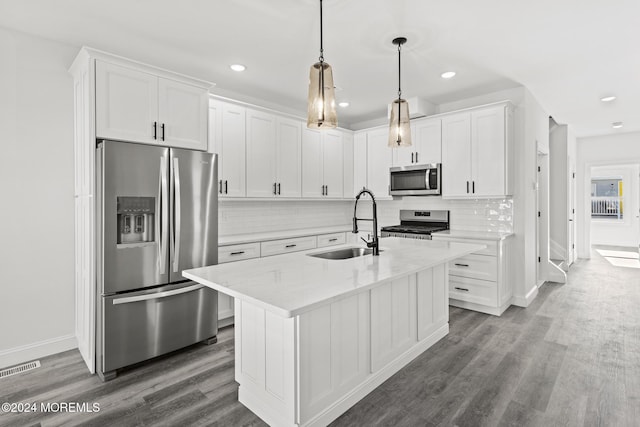 kitchen featuring a center island with sink, appliances with stainless steel finishes, hanging light fixtures, sink, and white cabinetry