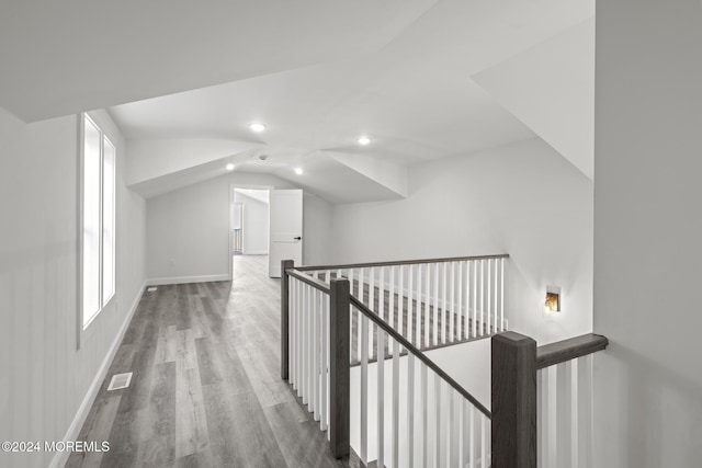 corridor with a healthy amount of sunlight, vaulted ceiling, and hardwood / wood-style flooring