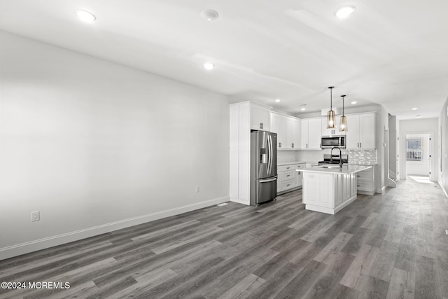 kitchen featuring appliances with stainless steel finishes, white cabinetry, hanging light fixtures, a center island with sink, and dark wood-type flooring