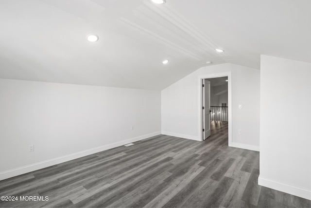 additional living space featuring dark wood-type flooring and vaulted ceiling