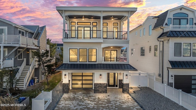 back house at dusk with a balcony and a garage