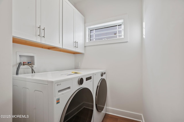 clothes washing area featuring cabinets, dark wood-type flooring, and washing machine and clothes dryer