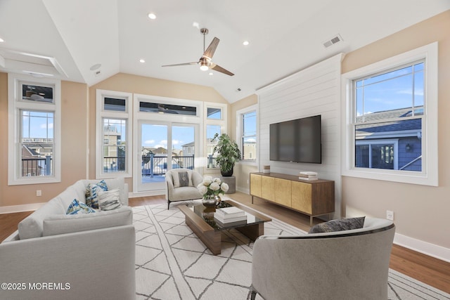 living room with ceiling fan, vaulted ceiling, and light wood-type flooring