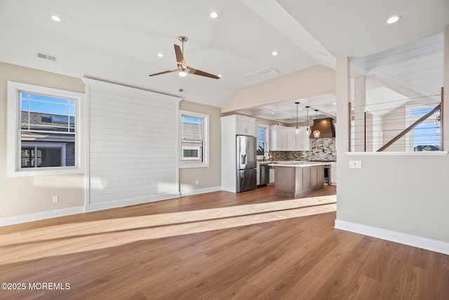 unfurnished living room featuring ceiling fan, sink, light hardwood / wood-style floors, and vaulted ceiling