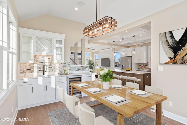 dining room featuring lofted ceiling, sink, wine cooler, ceiling fan, and light wood-type flooring