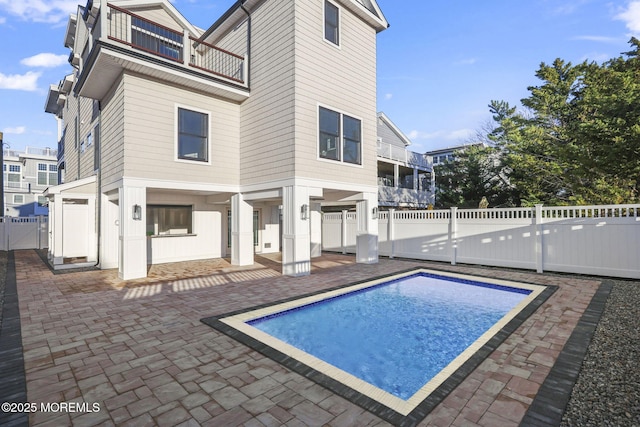 back of house featuring a fenced in pool, a patio area, and a balcony