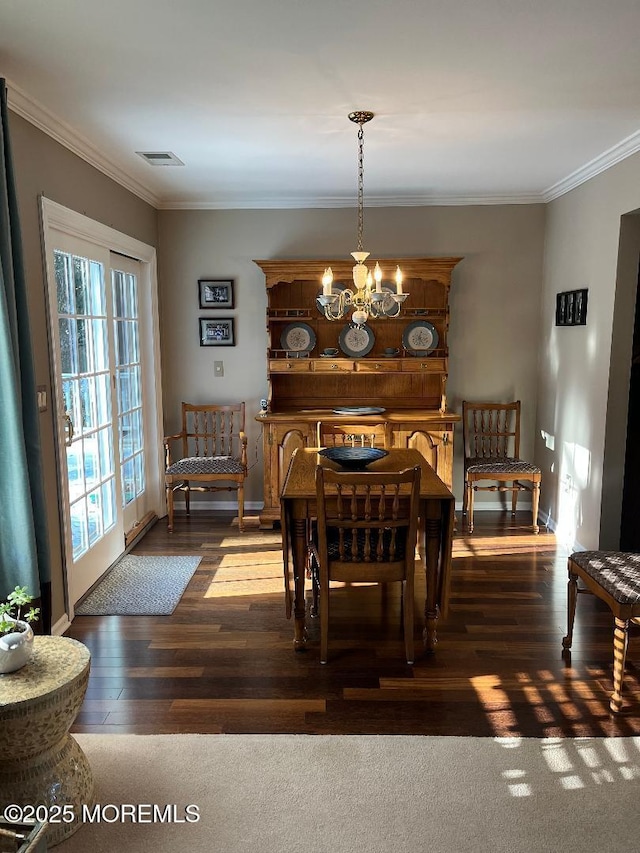 dining area featuring dark hardwood / wood-style flooring, ornamental molding, and a notable chandelier