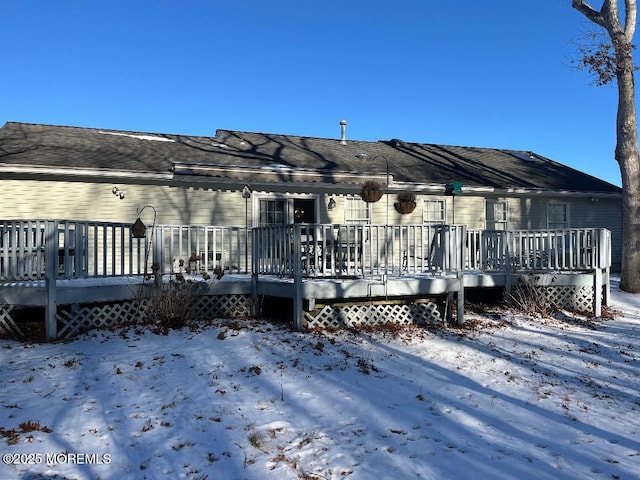 snow covered house with a wooden deck